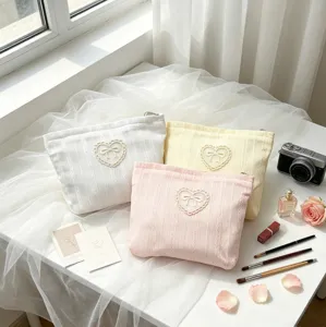Set of three pastel-colored makeup bags with heart-shaped bow-knot embroidery detail