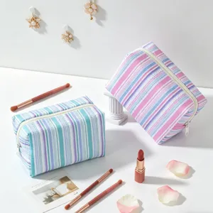 Detail of blue and pink seersucker striped makeup bags on a white aesthetic background