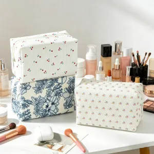 Blumige Cord-Kosmetiktaschen mit Make-up-Pinseln und Hautpflege-Flaschen präsentiert