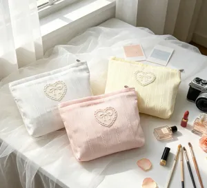 Collection of pastel bow makeup bags with lace heart detail on a soft white background