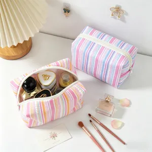 Detailed macro of striped seersucker makeup bags showing storage capacity and texture