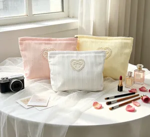 Three elegant bow cosmetic bags in pastel shades displayed with beauty accessories