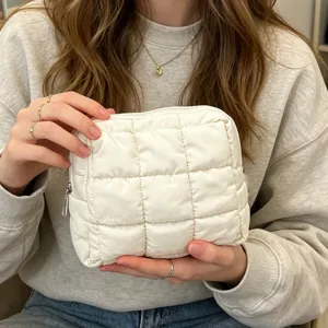 Vista a mano de un neceser acolchado blanco que muestra su textura suave y mullida