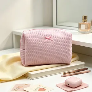 Vista detallada de un neceser rosa con textura de gofre y un lazo de decoración fina