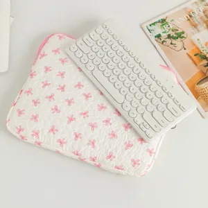 Süße Laptoptasche mit rosa Schleifenmuster und weißer Tastatur auf einem Schreibtisch