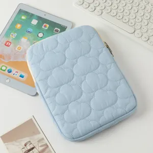 Dettaglio della custodia per iPad trapuntata azzurra con ricamo a nuvola su scrivania