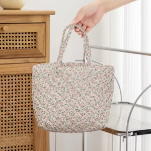 Primer plano de un neceser acolchado con estampado floral sujetado por una mano elegante