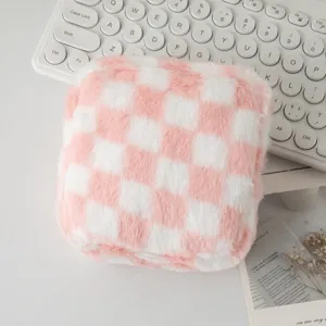 Primo piano di borsa cosmetica in peluche a scacchi rosa e bianca su tastiera bianca