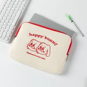 Housse d'ordinateur brodée lapin sur bureau avec clavier et stylo vert.