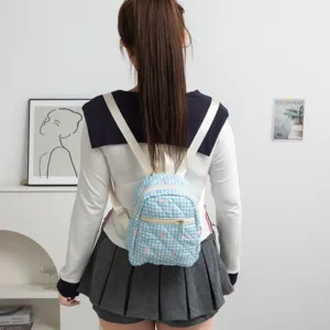 Mini mochila de cuadros azules con lazos rosas bordados mostrada en una modelo