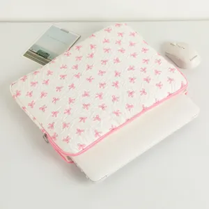 Detailansicht einer Laptoptasche mit rosa Schleifenmuster und weißem Laptop