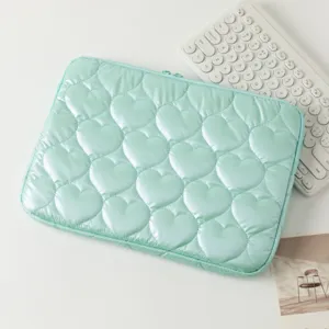 Detalle de la funda para portátil verde menta con acolchado de corazones y textura suave.