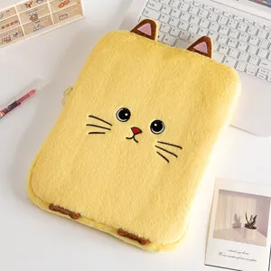 Detail view of a cute yellow plush cat laptop sleeve on a desk with keyboard and card