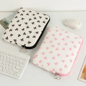 Gesteppte Laptop-Hülle mit eleganten Schleifenmustern in Schwarz und Rosa auf dem Schreibtisch