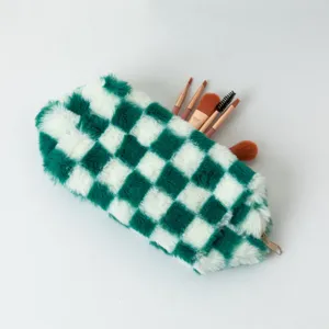 Vue détaillée d'une trousse en peluche à damier vert et blanc avec pinceaux de maquillage