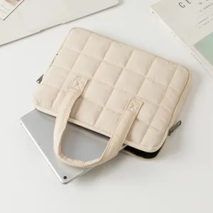 Custodia per laptop trapuntata beige per MacBook e tablet con dispositivo argentato.