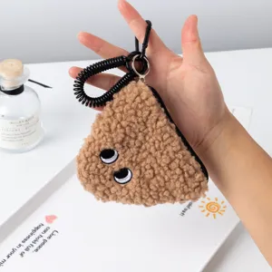 Close-up of a plush onigiri coin purse held in hand, showing soft brown lamb wool texture.