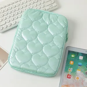 Primer plano del patrón de corazón acolchado verde menta en la funda para tableta con accesorios.