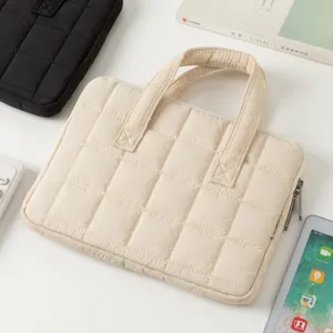 Vista dettagliata di una borsa per laptop trapuntata beige con robusti manici superiori