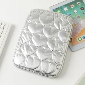 Vista detallada de una funda para tableta acolchada con corazones plateados en mesa