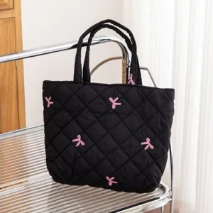 Detalle de bolso shopper acolchado negro con patrones de mariposas bordadas