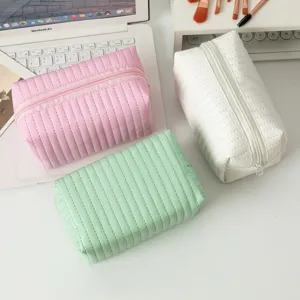 Pastelkleurige PU-leren make-uptassen met gewatteerde textuur op een wit bureau