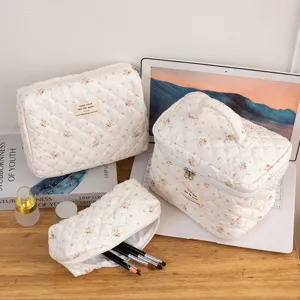 Detailed view of white quilted cotton cosmetic bags with floral patterns on a desk