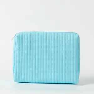 Nahaufnahme einer hellblauen gesteppten Kosmetiktasche mit vertikalen Nähten für Reisen