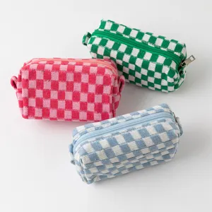 Drie geruite gebreide make-uptassen in roze, groen en blauw op witte achtergrond