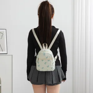 Lindo mini mochila blanca acolchada con lazos azules bordados vista trasera en modelo