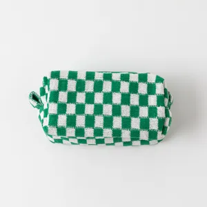 Gedetailleerd bovenaanzicht van een groen-witte gebreide make-up tas met schaakbordpatroon