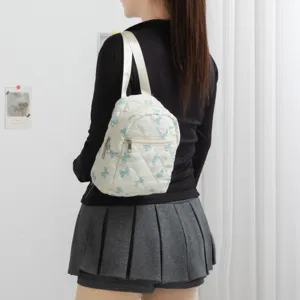 Vista detallada de mini mochila acolchada blanca con estampado de mariposa azul en modelo