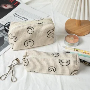 Detalle del neceser de pana con estampado de carita sonriente negra y estuche escolar