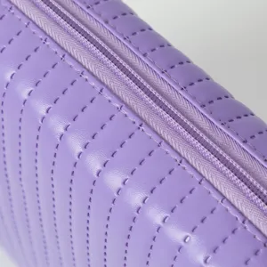 Detailansicht einer lila gesteppten Kosmetiktasche mit Reißverschluss und feiner Textur.