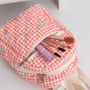 Detalle de la mochila de cuadros rosa con lazos bordados y gran bolsillo frontal.