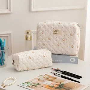 Floral quilted cotton cosmetic bag set with zipper closure on a white table