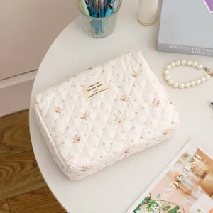 Quilted floral cotton makeup bag placed on a white round table with lifestyle props