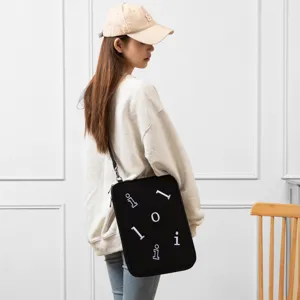 Detailed view of black crossbody tablet sleeve with white letter patterns worn by model