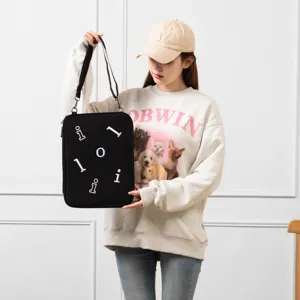 Detailed view of black crossbody laptop sleeve with letter patches and adjustable shoulder strap