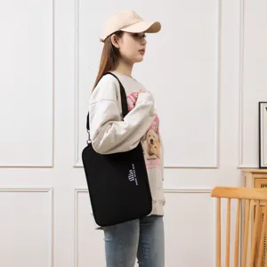 Minimalist black crossbody laptop sleeve bag with adjustable shoulder strap worn by a model