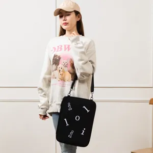 Asian model carrying a black 13.3-inch laptop crossbody bag with letter patches.