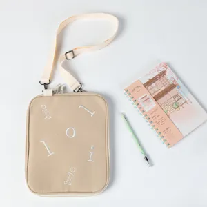 Beige minimalist iPad crossbody bag with adjustable shoulder strap and embroidered letters