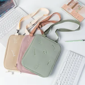 Three colorful laptop sleeves in beige, pink, and green on a minimalist white desk