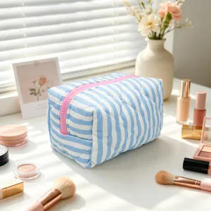Lifestyle scene of a blue and white striped quilted makeup bag with makeup accessories