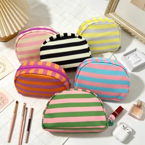 Collection of vibrant striped shell-shaped makeup bags displayed with cosmetic accessories.