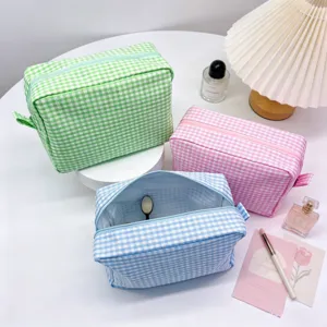 Three pastel gingham seersucker makeup bags in green pink and blue colors for travel