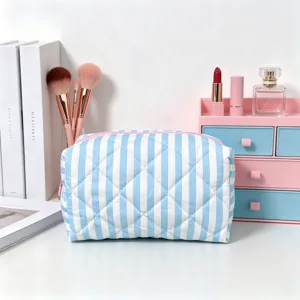 Blue and white striped quilted cosmetic bag on a stylish vanity desk with makeup