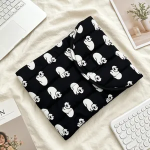 Primer plano de una funda acolchada negra para portátil con patrón de gato blanco