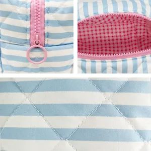 Close-up of blue striped quilted makeup bag showing pink zipper and checkered lining