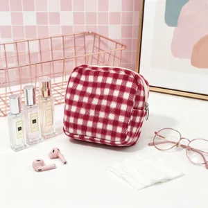Red and white checkered wool pouch with perfumes and glasses on a pink background